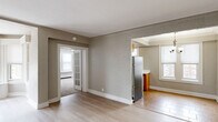 This well-organized single-floor residence offers two bedrooms, one bathroom, and a thoughtful layout connecting living, dining, and kitchen areas. The living room is a standout feature, highlighted by a graceful curved bay window that floods the space with natural light and adds architectural character. Light hardwood flooring runs throughout the main living and dining areas, complementing the neutral, textured wall finishes found throughout the home.

The kitchen is efficiently designed in an L-shaped configuration, featuring warm oak cabinetry, white countertops, tile flooring, and stainless steel appliances including a full-size refrigerator and dishwasher. A window above the sink provides natural light to the workspace.

Both bedrooms are carpeted and generously proportioned. The primary bedroom is notably spacious, offering built-in cabinetry with drawers, an open closet with integrated shelving, a ceiling fan, and multiple windows that bring in ample daylight. The second bedroom also includes a ceiling fan, a window, and access to additional storage.

The bathroom features classic white hex tile flooring and a distinctive arched walk-in shower alcove, lending a timeless, architectural touch. A connecting hallway ties all rooms together, creating a cohesive and functional flow throughout the residence.