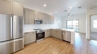 Located in Gilbert, Arizona, this well-appointed one-bedroom, one-bathroom unit offers a thoughtfully designed layout that maximizes its efficient footprint. The open-concept living and kitchen area is anchored by light wood-look flooring that flows throughout the main living spaces, creating a clean and cohesive aesthetic. The kitchen is a standout feature, equipped with a full suite of stainless steel appliances including a refrigerator, range, microwave, and dishwasher, complemented by warm taupe shaker-style cabinetry, white quartz countertops, a textured tile backsplash, and recessed lighting overhead. A ceiling fan in the main area enhances airflow and comfort. The bedroom offers plush carpeting, a ceiling fan with light fixture, and a window that allows in natural light. The bathroom is finished with an extended white quartz vanity, undermount sink, modern fixtures, and an LED-backlit mirror, adding a contemporary touch. A dedicated in-unit laundry area features a stacked washer and dryer, providing added convenience. The unit's crisp white walls, clean finishes, and consistent design language throughout create a bright, modern atmosphere ideal for comfortable everyday living.