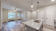 Located at 2988 Radio Rd in River Falls, WI, this well-appointed 2-bedroom, 2-bathroom unit offers a thoughtfully designed single-floor layout with modern finishes throughout. The open-concept kitchen and living area serves as the heart of the home, anchored by a striking granite-topped center island with an undermount sink and elegant pendant lighting. Gray shaker-style cabinetry, stainless steel appliances — including a refrigerator, range, and microwave — and durable wood-look plank flooring complete the kitchen's contemporary aesthetic. The living room is bright and airy, featuring a ceiling fan and a large window that invites natural light. Both bedrooms are carpeted for comfort, with windows providing outdoor views and baseboard heating units. The spacious primary bedroom includes its own dedicated bathroom, outfitted with gray vanity cabinetry, a white countertop, and wood-look flooring. The second bathroom features a full tub-shower combo, a matching gray vanity, and clean, neutral finishes. A dedicated closet provides additional storage. Throughout the unit, a cohesive neutral color palette, clean lines, and quality materials create a modern and welcoming ambiance.