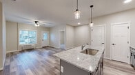 Located at 2988 Radio Rd in River Falls, WI, this well-appointed 2-bedroom, 2-bathroom unit offers a thoughtfully designed single-floor layout with modern finishes throughout. The open-concept kitchen and living area serves as the heart of the home, anchored by a striking granite-topped center island with an undermount sink and elegant pendant lighting. Gray shaker-style cabinetry, stainless steel appliances — including a refrigerator, range, and microwave — and durable wood-look plank flooring complete the kitchen's contemporary aesthetic. The living room is bright and airy, featuring a ceiling fan and a large window that invites natural light. Both bedrooms are carpeted for comfort, with windows providing outdoor views and baseboard heating units. The spacious primary bedroom includes its own dedicated bathroom, outfitted with gray vanity cabinetry, a white countertop, and wood-look flooring. The second bathroom features a full tub-shower combo, a matching gray vanity, and clean, neutral finishes. A dedicated closet provides additional storage. Throughout the unit, a cohesive neutral color palette, clean lines, and quality materials create a modern and welcoming ambiance.
