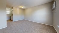 Located at 530 Sundown Dr in Independence, Missouri, this single-floor unit offers a straightforward and functional layout comprising a living room and a full bathroom. The living room serves as the central space of the unit, featuring neutral beige walls, plush wall-to-wall carpeting, and a textured ceiling that adds subtle visual interest. A large window along one wall floods the room with natural light and provides a view of the surrounding greenery, creating a bright and welcoming atmosphere. The entry door opens directly into this space, and built-in closet doors offer convenient storage solutions. Flush-mount ceiling lighting ensures the room remains well-lit at all times. The transition from carpet to hardwood-style flooring marks the entry into the bathroom and adjoining areas. The bathroom is clean and efficiently designed, featuring a walk-in shower unit with a grab bar for added safety, a standard toilet, and a wall-mounted shelf. The hardwood-style flooring in the bathroom is easy to maintain and provides a practical contrast to the carpeted living area. The overall aesthetic of the unit is simple and neutral, with light-toned walls throughout that contribute to an open and airy feel despite the compact footprint. This unit is well-suited for an individual seeking a manageable, easy-to-maintain living space in Independence, MO.