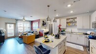 This thoughtfully designed 2-bedroom, 2-bathroom residence in Huntsville, Alabama offers a single-level open-concept layout that maximizes functionality and flow. The combined kitchen and living area serves as the heart of the home, where a sleek kitchen impresses with white cabinetry, granite countertops, a subway tile backsplash, stainless steel appliances, and a central island with bar seating illuminated by modern pendant lighting. The living room is anchored by a bold accent wall and large windows with patio door access, flooding the space with natural light and offering outdoor views. Wood-style flooring runs throughout, lending warmth and visual continuity across all rooms. Both bedrooms are comfortably sized, each featuring windows that invite natural light, with the primary bedroom offering ample space for a full furniture arrangement. The two bathrooms are finished with granite-topped vanities and modern cabinetry; one includes a shower-tub combination, while the other features a clean single-vanity layout. A dedicated closet provides additional storage. The overall aesthetic is contemporary and cohesive, blending neutral tones with vibrant accent elements for a modern, welcoming ambiance.
