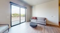 Located at 128 Langdon Street in Madison, Wisconsin, this contemporary 2-bedroom, 2-bathroom apartment offers 820 square feet of thoughtfully designed single-floor living. The open-concept kitchen and living area serves as the heart of the unit, featuring gray shaker cabinets, white quartz countertops, a subway tile backsplash, stainless steel appliances, and a peninsula island with bar seating. Striking dome pendant lights with gold interiors add a modern design accent. The living room extends to a private balcony through large sliding glass doors, offering open views of the Madison skyline and surrounding greenery. Both bathrooms are finished with gray vanities, white quartz countertops, and stylish round black-framed mirrors with chrome hardware accents. The primary bedroom measures 160 square feet and features a window with outdoor views. A dedicated walk-in closet with wire shelving provides practical storage. The second bedroom is bright and comfortably sized. Wood-style flooring runs throughout the entire unit, creating a cohesive and warm aesthetic. Clean neutral walls and abundant natural light contribute to an open, airy atmosphere throughout this well-appointed Madison apartment.