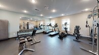 Located at 315 King St in La Crosse, Wisconsin, this fitness center is a comprehensively outfitted single-level facility designed to support a full range of workout routines. The space features a practical and modern interior with neutral-toned walls, recessed lighting, and a combination of rubber and hardwood-style flooring that accommodates both cardio and strength training areas.

The cardio zone is well-stocked with multiple treadmills, elliptical trainers, a stair climber, and a rowing machine, providing ample options for aerobic exercise. A large wall-mounted mirror runs along one section of the room, visually expanding the space and allowing users to monitor their form during workouts.

The strength training area includes a multi-functional cable machine, a full dumbbell rack with varying weights, adjustable weight benches, and a collection of stability balls. Natural light filters in through windows along the walls, contributing to an open and energizing atmosphere.

Additional amenities include a water station and what appears to be a dedicated storage area. The space is accessed through double glass doors and maintains a clean, well-organized layout throughout, making it a functional and inviting facility for users of all fitness levels.