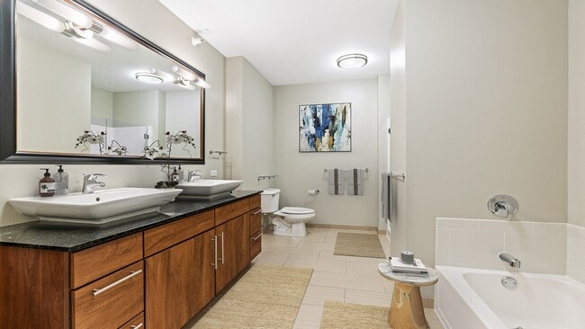 Our penthouse master bathroom features double sinks, a glass surround shower, and a bath perfect for unwinding after a long day! - Flair Tower
