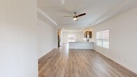 This single-story home in Athens, Alabama offers a well-designed open-concept layout across three bedrooms and two bathrooms. The living and kitchen areas flow seamlessly together, anchored by light wood-look flooring and crisp white walls throughout. A tray ceiling with a ceiling fan adds architectural interest to the living room, while recessed lighting and multiple windows fill the space with natural light.

The kitchen is a functional centerpiece, featuring a large peninsula with a granite countertop and undermount sink, warm-toned cabinetry, stainless steel appliances, and views into the living area. A door provides access to the exterior, enhancing connectivity between indoor and outdoor spaces.

The primary bedroom is generously sized and includes a walk-in closet with wire shelving. The en-suite bathroom is equipped with a double-sink vanity featuring granite countertops, a framed glass-enclosed shower, and wood-look flooring. A dedicated laundry room accommodates a full-size washer and dryer with overhead wire shelving.

Two additional bedrooms share a second bathroom. The attached garage features a concrete floor, a water heater, and direct interior access, completing this practical and move-in-ready home.