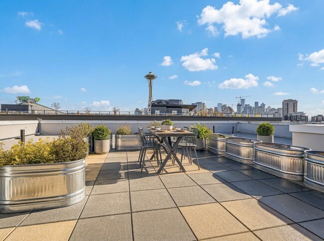 The rooftop deck at 306 Queen Anne offers outdoor dining seating, planters, and direct views of the Space Needle. - 306 Queen Anne