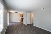 Located on Magnolia Avenue in Riverside, California, this single-story space presents a clean, updated interior with a cohesive neutral color palette throughout. The open living area is a notable feature, offering generous proportions accentuated by wood-look luxury vinyl flooring that extends seamlessly across the space. Natural light enters through horizontal-slatted blinds on multiple windows and a sliding glass door fitted with vertical blinds, contributing to a bright and airy atmosphere. A ceiling fan serves the living area, enhancing comfort year-round.

The kitchen is well-appointed with warm-toned wood cabinetry, white countertops, and a full suite of stainless steel appliances, including a refrigerator, electric range, over-the-range microwave, and dishwasher. Recessed lighting and a window keep the space functional and well-lit.

The bedrooms each feature the same wood-look flooring, neutral walls, and window blinds that invite natural light. Several rooms are equipped with ceiling fans. The bathroom includes a shower-tub combination with matte black fixtures, a toilet, and matching flooring, maintaining the consistent modern aesthetic found throughout the space.