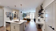 This well-appointed single-story residence in Southern Pines, NC offers a thoughtful layout across a comfortable footprint, featuring one bedroom, two full bathrooms, a dedicated office, and an open-concept living and kitchen area. Warm hardwood-style flooring flows throughout, tying the spaces together cohesively.

The kitchen is a standout, boasting white shaker cabinetry, stainless steel appliances, and a central island with seating for three — illuminated by modern pendant lights. It flows seamlessly into the living room, where French doors invite natural light and provide access to an outdoor area. The living room is an inviting space accented by a ceiling fan and stylish wall art.

The primary bedroom features a deep blue accent wall, a ceiling fan, and a large window that fills the room with natural light. It connects to a private en-suite bathroom with a glass-enclosed shower and walk-in closet with wire shelving. A second full bathroom includes a tub-shower combination with matte black fixtures.

The dedicated office is a refined space with moody slate-toned walls, wood shelving units with integrated cabinetry, and ample room for a full desk setup. Two hallways and an additional closet provide generous storage throughout this polished and functional home.