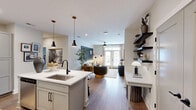 This well-appointed single-story residence in Southern Pines, NC offers a thoughtful layout across a comfortable footprint, featuring one bedroom, two full bathrooms, a dedicated office, and an open-concept living and kitchen area. Warm hardwood-style flooring flows throughout, tying the spaces together cohesively.

The kitchen is a standout, boasting white shaker cabinetry, stainless steel appliances, and a central island with seating for three — illuminated by modern pendant lights. It flows seamlessly into the living room, where French doors invite natural light and provide access to an outdoor area. The living room is an inviting space accented by a ceiling fan and stylish wall art.

The primary bedroom features a deep blue accent wall, a ceiling fan, and a large window that fills the room with natural light. It connects to a private en-suite bathroom with a glass-enclosed shower and walk-in closet with wire shelving. A second full bathroom includes a tub-shower combination with matte black fixtures.

The dedicated office is a refined space with moody slate-toned walls, wood shelving units with integrated cabinetry, and ample room for a full desk setup. Two hallways and an additional closet provide generous storage throughout this polished and functional home.