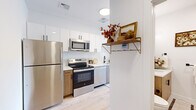 Located at 821 East Main Street in Stamford, Connecticut, this efficiently designed 2-bedroom, 1-bathroom residence offers a thoughtfully arranged single-floor layout with contemporary finishes throughout. Light hardwood flooring runs continuously across the space, lending a clean, cohesive aesthetic that enhances the sense of openness.

The kitchen is a standout feature, outfitted with a full suite of stainless steel appliances — including a refrigerator, electric range, over-the-range microwave, and dishwasher. White upper cabinetry is paired with warm wood-toned lower cabinets and crisp white countertops, creating a modern yet inviting contrast. A decorative wall-mounted shelf with gold brackets adds a stylish accent.

The primary bedroom is generously proportioned and benefits from large windows that invite abundant natural light and offer views of the surrounding Stamford neighborhood. The room accommodates a full living and sleeping arrangement with ease.

The bathroom features a wood-vanity with a white countertop, an undermount sink, matte black fixtures, a large framed mirror with overhead lighting, and tile flooring — delivering a clean, modern finish.

Throughout the residence, white walls and recessed lighting maintain a bright, neutral backdrop. Large windows in the living areas frame outdoor views, further enhancing the airy feel of this well-appointed Stamford home.