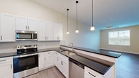 Located at 601 Flaugherty Run Rd in Coraopolis, PA, this thoughtfully designed 2-bedroom, 2-bathroom residence offers a comfortable and functional single-floor layout. The open-concept living and dining area flows seamlessly into a well-equipped kitchen, which features white shaker-style cabinetry, dark countertops, stainless steel appliances including a refrigerator, range, microwave, and dishwasher, and a peninsula with pendant lighting overhead — ideal for both everyday living and entertaining. Light wood-style flooring extends throughout the home, complementing the warm, neutral wall tones and crisp white trim. The hallway connecting the bedrooms is wide and well-lit, with recessed lighting and multiple closets providing generous storage. The spacious primary bedroom offers ample room and direct access to a private bathroom, which includes a white vanity with dark countertops, a large mirror, and grab bars. The second bedroom is equally well-proportioned. A second full bathroom mirrors the same clean, contemporary design. Additional highlights include a dedicated laundry area, a private balcony, and a total of seven closets distributed throughout the home, ensuring practical storage at every turn.