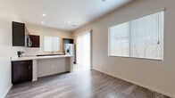 This single-story unit offers a thoughtfully arranged floor plan that maximizes functionality within a compact footprint. The open-concept layout connects the kitchen and living area into one cohesive space, promoting an efficient and comfortable flow. Wood-look flooring runs consistently throughout, lending a warm, unified aesthetic to the interior.

The kitchen is a standout feature, equipped with a full suite of stainless steel appliances, including a French door refrigerator with ice and water dispenser, an electric range, built-in microwave, and dishwasher. Rich dark-brown cabinetry extends to the upper and lower walls, providing ample storage, while light-toned countertops offer a clean contrast. A peninsula with additional counter space adds functionality and subtly defines the boundary between the kitchen and living area.

The living room is bright and open, benefiting from natural light through windows fitted with horizontal blinds. A sliding glass door with vertical blinds provides access to the exterior. Neutral beige walls complement the flooring and create a calm, versatile backdrop.

The bedroom is a comfortable size, featuring two windows that allow natural light from multiple angles, along with a ceiling-mounted ventilation unit. The space maintains the same neutral tones and wood-look flooring found throughout, creating a cohesive, modern feel.
