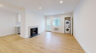 Located in the Mar Vista neighborhood of Los Angeles, this 2-bedroom, 2-bathroom single-story home offers a clean, modern aesthetic throughout. Light oak wood flooring runs continuously across every room, creating a warm and cohesive feel. The open living room serves as the heart of the home, anchored by a tiled fireplace and a glass-paned door that invites natural light. A stacked washer and dryer unit is conveniently tucked into the living area. The galley-style kitchen is well-appointed with gray shaker cabinetry, white quartz countertops, stainless steel appliances including a gas range, microwave, and refrigerator, and a window above the sink for added brightness. The spacious primary bedroom features recessed lighting, a dedicated walk-in closet, and a private en-suite bathroom with a glass-enclosed shower and gray vanity. The second bedroom includes mirrored sliding closet doors and a natural light window. Both bathrooms are finished with hexagonal tile flooring, gray cabinetry, and white quartz countertops — one featuring a soaking tub with subway tile surround. Recessed lighting throughout and crisp white walls complete the bright, minimalist interior of this thoughtfully updated home.