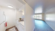 Located in Dallas's vibrant 75206 zip code, this one-bedroom, one-bathroom home offers a well-organized and efficiently designed layout across a single floor. Wood-style flooring runs throughout the main living areas, lending warmth and visual continuity to the space.

The living room is bright and open, benefiting from a large window that invites natural light and provides views of the surrounding neighborhood. A wall sconce adds a touch of ambient lighting, complementing the clean white walls and textured ceiling.

The kitchen is positioned adjacent to the living area and features white cabinetry, granite-style countertops, a single-basin sink, and a coil-burner range with overhead ventilation — offering all the essentials in a compact, functional space.

The bedroom is a comfortable, well-proportioned room highlighted by a large window with vertical blinds, allowing for generous natural light and outdoor views. It is paired with a dedicated walk-in closet that includes built-in shelving and a bench, providing practical and ample storage.

The bathroom is equipped with a vanity featuring a granite-style countertop, a large framed mirror, and a shower-tub combination. A connecting hallway ties all rooms together, creating a logical and easy-to-navigate flow throughout the home.