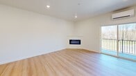 This thoughtfully designed one-bedroom, one-bathroom apartment in Vancouver, WA offers a bright, modern living experience across a well-utilized single floor. The open-concept main area seamlessly integrates the living room, dining space, and kitchen, all finished with light-toned luxury vinyl plank flooring that runs throughout the unit. The kitchen is a standout feature, boasting grey shaker-style cabinetry, a white subway tile backsplash, quartz countertops with a striking veined pattern, a center island, and a full suite of stainless steel appliances including a refrigerator, gas range, microwave, and dishwasher. The living area is anchored by a sleek wall-mounted electric fireplace and opens via sliding glass doors to a private balcony overlooking natural greenery. A wall-mounted mini-split HVAC system provides efficient climate control. The bedroom is comfortably sized, featuring a sliding closet, a dedicated mini-split unit, and a bright window with outdoor views. The bathroom includes a dual-sink vanity, tile flooring, and a full soaking tub. Additional conveniences include in-unit laundry, a hallway with extra closet space, and recessed lighting throughout.