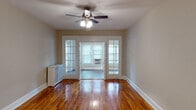 Located at 2700 Q St NW in the heart of Washington, DC's historic Georgetown neighborhood, this well-appointed residence offers a thoughtfully designed single-floor layout with a blend of classic charm and modern updates. Rich hardwood floors extend throughout the main living areas, catching natural light and adding warmth to each room. The living area is a standout space, featuring elegant French doors that connect to an adjacent sunlit room, ceiling fans, and crisp white trim that frames the neutral-toned walls. The sunroom beyond the French doors is bathed in natural light through a row of large windows and showcases a distinctive herringbone-patterned floor, creating a versatile and inviting space. The bedrooms continue the hardwood flooring theme, each equipped with ceiling fans, natural light from double windows, and radiator units. The kitchen has been updated with white cabinetry, granite countertops, stainless steel appliances, and tile flooring, offering both style and functionality. The bathroom is finished in classic white, featuring penny-tile flooring, a tub-shower combination, and a window for natural ventilation. A paneled entry door with modern hardware provides a welcoming and secure entry point to this charming Georgetown residence.