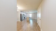 This single-story, one-bedroom, one-bathroom home offers a thoughtfully designed open-concept layout that maximizes its generous living space. Light-toned luxury vinyl plank flooring flows seamlessly throughout, lending a cohesive and contemporary feel to every room.

The combined kitchen and living area serves as the heart of the home. The kitchen is a standout feature, showcasing white shaker-style cabinetry, gleaming granite countertops, a classic subway tile backsplash, and a full suite of stainless steel appliances. A large central island with an integrated sink and elegant pendant lighting above provides ample workspace and casual dining potential. The living room benefits from multiple windows and a glass-paneled exterior door that invites natural light and outdoor views, complemented by a ceiling fan overhead.

The spacious bedroom is a comfortable retreat, featuring a ceiling fan, a sizable window overlooking the outdoors, and direct access to the bathroom. The bathroom is cleanly designed with a soaking tub accented by tile surround and brushed nickel fixtures, alongside a separate toilet area and a vanity with granite countertops. Throughout the home, neutral warm-gray walls, bright white trim, and recessed lighting create a fresh, move-in-ready ambiance.
