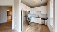 Located at 400 Rhett St in the heart of downtown Greenville, SC, this one-bedroom, one-bathroom unit offers a thoughtfully arranged floor plan that maximizes every square foot. The open living area features warm hardwood-style flooring and neutral walls that create a clean, contemporary atmosphere, with a window providing natural light and views of the surrounding area.

The kitchen is a functional highlight, featuring crisp white cabinetry extending to the ceiling, dark granite countertops, a classic subway tile backsplash, and a full suite of stainless steel appliances including a refrigerator, range, microwave, and dishwasher. Track lighting adds a modern touch overhead.

The bedroom is carpeted for comfort, fitted with a ceiling fan, and accessed through stylish double doors. It connects to a dedicated walk-in closet outfitted with wire shelving systems on multiple levels, offering organized storage capacity. A stacked in-unit washer and dryer is conveniently tucked into a dedicated laundry nook near the main living area.

The bathroom includes a full soaking tub and shower combination with tiled surround and built-in shelving, complemented by tile flooring and granite-accented vanity. Throughout the unit, a consistent neutral color palette and clean finishes contribute to a cohesive, move-in-ready aesthetic.