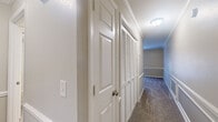 Located at 2160 N Thompson Ln in Murfreesboro, TN, this one-bedroom, one-bathroom unit offers a well-organized, single-floor layout designed for efficient everyday living. The open living area features warm neutral-toned walls, crown molding, and plush carpet flooring, creating a comfortable and inviting atmosphere. French doors lead out to a balcony, allowing natural light to flow into the living space. The kitchen is situated adjacent to the living area and is equipped with rich wood-toned cabinetry, a white refrigerator, dishwasher, and a sink with countertop workspace, all set on durable wood-style flooring. A hallway connects the main living space to the private quarters, featuring louvered closet doors and clean white trim throughout. The bedroom is generously sized, carpeted, and fitted with a ceiling fan and a window that brings in natural light. It includes a dedicated walk-in style closet and provides direct access to the bathroom. The bathroom offers a full tub-shower combination with a clean white surround and wood-style flooring. Crown molding and consistent neutral finishes throughout the unit contribute to a cohesive and polished aesthetic.
