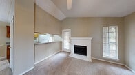 This single-floor residence offers a well-organized layout designed for comfortable everyday living. The main living area is a standout, featuring dramatically vaulted ceilings that lend a sense of openness and volume to the space. A white-mantled brick fireplace serves as the focal point of the living room, complemented by a ceiling fan overhead and access to the outdoors through a windowed door. Natural light filters in through multiple windows fitted with blinds, creating a bright and welcoming atmosphere throughout.

The kitchen is functional and well-equipped, featuring warm wood cabinetry, granite-look countertops, a full suite of white appliances including a refrigerator, electric range with overhead microwave, and dishwasher. Light hardwood-style flooring runs through the kitchen, which connects seamlessly to the living and dining areas via a pass-through counter. The dining area is highlighted by a pendant light fixture.

The bedrooms are generously sized with plush carpeting and ceiling fans, offering a quiet retreat. Each room benefits from good natural light through windows with outdoor views. The bathroom includes a full tiled tub-and-shower combination with chrome fixtures. Throughout the residence, neutral toned walls and textured ceilings provide a cohesive and move-in ready aesthetic.
