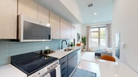 Located at 700 Hamilton Avenue in Nashville, TN, this thoughtfully designed one-bedroom, one-bathroom unit maximizes every inch of its compact footprint with a smart, open-concept layout. Light hardwood flooring and crisp white walls run throughout, creating a clean, modern aesthetic that feels bright and cohesive.

The galley-style kitchen is outfitted with two-tone cabinetry — warm wood uppers paired with dark lower cabinets — complemented by a light quartz countertop, a light blue subway tile backsplash, and stainless steel appliances including a refrigerator, electric range, microwave, and dishwasher. The kitchen flows seamlessly into a combined dining and living area anchored by a large window that floods the space with natural light and offers outdoor views.

The bedroom is generously proportioned relative to the overall footprint, featuring soaring ceilings, a ceiling fan, large picture windows that invite abundant daylight and treetop views, and a double-door closet for storage. The bathroom is finished with a warm wood vanity, matte black fixtures, a framed mirror, and a tiled tub-shower combination with dark subway tile detailing. A dedicated laundry area and utility room round out the unit's functional offerings.