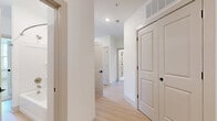 Located at 5025 Huntly Ridge St in Charlottesville, VA, this single-floor, two-bedroom, one-bathroom home offers a clean, modern aesthetic throughout. Light wood-tone flooring flows through the main living areas, complemented by crisp white walls and abundant natural light from multiple windows fitted with blinds.

The kitchen is well-appointed with white shaker-style cabinetry, black hardware accents, a subway tile backsplash, stainless steel appliances including a refrigerator, range, microwave, and dishwasher, and a central island that adds both prep space and casual dining potential.

The spacious primary bedroom features direct outdoor access through a glass-panel door, allowing natural light and exterior views. The second bedroom is carpeted and bright, with a large window overlooking the neighborhood. Both bedrooms offer generous proportions, with the primary providing ample space for comfortable furnishing.

The bathroom is finished in a sleek, modern style with a white vanity, clean countertops, and a glass-enclosed walk-in shower with built-in shelving and brushed nickel fixtures. A dedicated laundry area with a front-loading Whirlpool washer is conveniently tucked within the unit. A hallway closet rounds out the practical storage offerings throughout this well-designed home.
