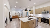 Located on East Colfax Avenue in Denver, this well-appointed 2-bedroom, 2-bathroom residence offers a thoughtfully designed single-level layout with modern finishes throughout. The open-concept living and dining area flows seamlessly into the kitchen, creating a bright, connected space ideal for both everyday living and entertaining. Recessed lighting and light wood-tone flooring run throughout, contributing to a clean, contemporary aesthetic.

The kitchen is outfitted with flat-front wood cabinetry featuring matte black hardware, white quartz countertops, a full upper and lower cabinet configuration, and stainless steel appliances, including a range and built-in microwave. A dedicated dining area sits adjacent, completing the open-plan arrangement.

Both bathrooms echo the home's modern design language, featuring warm wood vanities with white quartz tops, glass-enclosed showers, and light wood-look tile flooring. Each bedroom is generously proportioned with ample natural light, and the primary bedroom includes large windows with views to the exterior. Both bedrooms are supported by dedicated walk-in closets with multi-rod and shelving configurations, offering substantial storage. In-unit washer and dryer connections are also present, adding everyday convenience to this well-finished Denver residence.