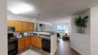 Located at 1201 Aragon Dr in Knightdale, NC, this single-floor, 3-bedroom, 2-bathroom home offers a well-designed open-concept layout ideal for both everyday living and entertaining. The kitchen is equipped with warm honey-toned cabinetry, dark countertops, black appliances including a gas range and refrigerator, and a peninsula with bar seating — perfect for casual dining. The kitchen flows seamlessly into the living room, which features hardwood-style flooring and natural light from large windows. A dedicated hallway connects the private bedroom wing to the main living areas. The spacious primary bedroom features plush carpeting, a ceiling fan, and a large window with outdoor views, complemented by a walk-in closet with wire shelving. Two full bathrooms serve the home, both featuring wood-toned vanities with white countertops and shower-tub combinations. One bathroom includes accessibility grab bars. The additional bedrooms are well-proportioned with carpeted floors. A dedicated closet provides extra storage. Throughout the home, neutral white walls and consistent finishes create a cohesive, clean aesthetic, making this a functional and inviting residence.