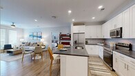 Located at 4000 Galantis Dr in Morehead City, NC, this well-appointed 2-bedroom, 2-bathroom single-floor residence offers a thoughtfully designed layout that maximizes comfort and functionality. The open-concept living, dining, and kitchen area serves as the heart of the home, featuring light wood-tone flooring that flows seamlessly throughout. The kitchen is outfitted with white shaker cabinetry, dark granite countertops, a subway tile backsplash, stainless steel appliances including a French door refrigerator and range, and a central island with a built-in sink — ideal for both meal prep and casual dining. The living room offers a bright, neutral palette, while a dedicated entrance and hallway provide a smooth transition into the private areas of the home. The spacious primary bedroom includes a ceiling fan, generous natural light from large windows, and access to a dual-sink bathroom with white cabinetry and a well-lit vanity mirror. The second bedroom is equally comfortable with its own ceiling fan. Three closets, including a walk-in with wire shelving systems, provide abundant storage, while a pantry and dedicated utility room add further convenience. An in-unit laundry room completes this practical and polished residence.
