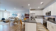 Located at 4000 Galantis Dr in Morehead City, NC, this well-appointed 2-bedroom, 2-bathroom single-floor residence offers a thoughtfully designed layout that maximizes comfort and functionality. The open-concept living, dining, and kitchen area serves as the heart of the home, featuring light wood-tone flooring that flows seamlessly throughout. The kitchen is outfitted with white shaker cabinetry, dark granite countertops, a subway tile backsplash, stainless steel appliances including a French door refrigerator and range, and a central island with a built-in sink — ideal for both meal prep and casual dining. The living room offers a bright, neutral palette, while a dedicated entrance and hallway provide a smooth transition into the private areas of the home. The spacious primary bedroom includes a ceiling fan, generous natural light from large windows, and access to a dual-sink bathroom with white cabinetry and a well-lit vanity mirror. The second bedroom is equally comfortable with its own ceiling fan. Three closets, including a walk-in with wire shelving systems, provide abundant storage, while a pantry and dedicated utility room add further convenience. An in-unit laundry room completes this practical and polished residence.