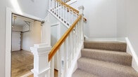Located at 408 Lighthouse Ln in East Lyme, Connecticut, this two-story home combines modern design with functional living across a well-organized floor plan. The main level showcases an open-concept layout where the kitchen flows seamlessly into the living area. The kitchen is appointed with granite countertops, stainless steel appliances including a refrigerator, range, microwave, and dishwasher, crisp white cabinetry, dark lower cabinetry accents, and a peninsula with pendant lighting overhead. Light hardwood flooring runs throughout the main living areas, contributing to a bright, airy atmosphere. Large windows and sliding glass doors invite abundant natural light and provide outdoor views. The attached garage offers convenient enclosed parking and additional storage space. A striking staircase with white painted balusters, square newel posts, and a warm wood handrail connects the two floors with classic craftsmanship. The upper level features carpeted bedrooms with generous closet space and easy access to well-finished bathrooms, including one with a glass-enclosed walk-in shower with textured tile surround and polished chrome fixtures. Throughout, a neutral color palette of soft grays and whites creates a clean, cohesive aesthetic that is both modern and welcoming.