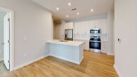 Located at 102 Kennedy Ridge Way in Mooresville, NC, this well-appointed 2-bedroom, 2-bathroom single-story unit offers a clean, modern aesthetic with thoughtfully designed spaces throughout. Light wood-tone flooring flows seamlessly across the entire unit, creating a warm and cohesive look.

The open-concept kitchen and living area serves as the heart of the home. The kitchen is outfitted with crisp white cabinetry, a subway tile backsplash, quartz countertops, a center island with an undermount sink, and a full suite of stainless steel appliances including a refrigerator, range, microwave, and dishwasher. Recessed lighting illuminates the space effectively.

The primary bedroom is a comfortable retreat with neutral walls and ample room for furnishings. The second bedroom features large windows with horizontal blinds that invite natural light and offer views of the surrounding neighborhood. Both bedrooms include closet space for storage.

Each bathroom is finished with white subway tile tub-and-shower surrounds, white vanities with quartz countertops, and brushed nickel fixtures, maintaining a consistent, contemporary style. The dedicated laundry room includes a washer, dryer, and overhead wire shelving for added functionality.

A hallway connects the bedrooms and bathrooms, and the living area provides access to a private outdoor space, enhancing the overall livability of this well-designed unit.