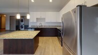 Located at 234–298 N St Clair St in downtown Toledo, Ohio, this single-floor unit offers a well-organized layout that balances open communal areas with private living spaces. The kitchen serves as a central highlight, featuring dark espresso cabinetry paired with white upper cabinets and granite countertops throughout, including on a functional center island. Stainless steel appliances, recessed and pendant lighting, and light wood-style flooring complete the contemporary aesthetic. In-unit stacked washer and dryer are conveniently integrated into the kitchen area.

The open living area adjoins the kitchen seamlessly, with the same light flooring extending throughout for a cohesive look. Bedrooms are carpeted for comfort, offering neutral tones, baseboard heating, closet storage, and access to natural light through windows fitted with roller shades. Dark-trimmed door frames provide a consistent design detail across the unit.

The bathroom is finished with a dark espresso vanity, a light countertop, a large mirror with overhead lighting, and a full tub and shower combination with chrome fixtures. The overall design is clean and modern, with a neutral color palette and consistent finishes creating a cohesive, move-in-ready environment.