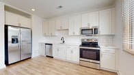 Located at 1115 Seigle Ave in Charlotte's vibrant 28205 corridor, this single-floor unit offers a clean, modern aesthetic defined by an open layout and consistent light wood vinyl plank flooring that flows seamlessly from room to room. The kitchen is a standout feature, outfitted with white shaker-style cabinetry extending to the ceiling, a classic white subway tile backsplash, light quartz countertops, and a full suite of stainless steel appliances including a refrigerator with ice maker, electric range, over-the-range microwave, and dishwasher. A matte black gooseneck faucet adds a refined contrast to the otherwise bright palette. The open floor plan connects the kitchen to a generously sized living area, illuminated by recessed lighting and crisp white walls that create a clean, airy atmosphere. The bedroom offers a comfortable footprint with natural light filtering in through windows framed in warm wood trim. The bathroom features a floating white vanity with dark countertop, undermount sink, matte black fixtures, and a large mirror with warm vanity lighting above. A dedicated laundry area with full-size washer and dryer hookups adds everyday convenience. The overall design is fresh, modern, and move-in ready.
