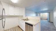 Located at 950 S Main St in Milpitas, California, this well-appointed one-bedroom, one-bathroom residence offers a thoughtfully designed single-floor layout. The kitchen is a functional highlight, featuring crisp white cabinetry extending to the ceiling for ample storage, light wood-style flooring, a stainless steel refrigerator, range, and dishwasher, and a peninsula counter with a built-in sink that opens toward the living area — ideal for everyday convenience. The living space transitions seamlessly from the kitchen, with soft carpeting and a sliding glass door that introduces natural light and outdoor views. The generously sized bedroom is carpeted and bathed in natural light from a dedicated window with exterior views. A walk-in closet provides substantial storage, enhancing the room's practicality. The bathroom is finished with wood-style flooring, white cabinetry, a granite-topped vanity with a brushed nickel faucet, a large mirror, and a tub-shower combination enclosed by sliding glass doors. Light, neutral tones throughout the unit create a clean, cohesive aesthetic, while textured ceilings add subtle architectural character. This residence combines efficient use of space with modern finishes in a well-connected Milpitas location.
