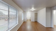 This 2-bedroom, 1-bathroom unit offers a well-organized single-floor layout designed for efficient, comfortable living. The living room serves as the central gathering space, featuring warm hardwood-style flooring, crisp white walls, and natural light streaming through blinds-fitted windows. A front entry door opens directly into this area, creating a welcoming arrival experience. The layout flows seamlessly into a hallway connecting the remaining rooms. The kitchen is equipped with light-toned cabinetry, a laminate countertop, a stainless steel sink, and overhead storage, providing functional workspace. Both bedrooms are carpeted in a neutral beige tone, offering a soft and quiet atmosphere. The primary bedroom is generously sized, while the second bedroom features its own window, filling the space with natural light. A dedicated closet adds convenient storage. The bathroom includes a vanity with a single sink set in a laminate countertop, a large mirror, and white tile wainscoting, maintaining a clean and practical aesthetic throughout. Consistent neutral wall colors and flush-mount ceiling lighting unify the interior, creating a cohesive, move-in-ready environment suited for a range of lifestyles.