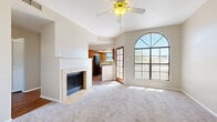 Located at 8115 N 18th St in Phoenix, AZ, this single-floor, 2-bedroom, 3-bathroom home offers a well-organized layout with a welcoming entrance, two hallways, and dedicated closet spaces. The living room is a standout, featuring a tile-surround wood-burning fireplace, plush carpeting, a ceiling fan, and a striking arched window that floods the space with natural light and frames outdoor views. French doors connect the living area to an additional room, enhancing the open feel. The kitchen is outfitted with warm wood cabinetry, light countertops, hardwood-style flooring, a breakfast bar peninsula, and stainless steel appliances including a range, microwave, and a black refrigerator, with a window above the sink for added brightness. Both bedrooms feature carpet, ceiling fans, and multi-pane windows with outdoor views; the primary bedroom includes its own closet. The three bathrooms include a clean, white soaking tub with chrome fixtures, and at least one bathroom features a wood-toned vanity with an overhead light fixture and hardwood-style flooring. Neutral tones throughout lend a cohesive, calm ambiance to the entire home.