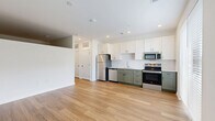 Located at 3939 State Line Rd in Kansas City, MO, this thoughtfully designed one-bedroom, one-bathroom unit offers a smart and functional layout across a single floor. The open-concept kitchen and living area serves as the heart of the space, featuring light wood-look flooring, recessed lighting, and a well-appointed kitchen with two-tone cabinetry — white upper cabinets paired with sage green lower cabinets — complemented by a full suite of stainless steel appliances including a refrigerator, range, microwave, and dishwasher. A hallway with sliding barn-style hardware connects the main living area to the private quarters, with two closets providing ample storage. The bedroom offers plush carpeting, a large window that draws in natural light, and a built-in sliding door closet. The full bathroom is finished in a clean, modern style with white subway tile surrounding the tub/shower combo, wood-look flooring, and white cabinetry with matte black hardware accents. A utility room and entrance area complete the layout. The unit presents a fresh, contemporary aesthetic with a consistent white and neutral color palette throughout.