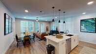 Located at 1701 Central Ave in St. Petersburg, Florida, this well-appointed single-floor residence offers a thoughtfully designed open-concept layout. The kitchen is a standout feature, showcasing white cabinetry, quartz countertops, stainless steel appliances, and a large center island with seating — illuminated by a trio of sleek pendant lights. The kitchen flows seamlessly into the living and dining areas, where light wood-style flooring, recessed lighting, and ceiling fans create a bright, comfortable atmosphere. Large windows throughout the main living space invite abundant natural light. The dining area accommodates a full-sized table and is accented by bold wall art, while a secondary flex room offers space for a home office or sitting room with plush carpeting and a ceiling fan. The bedrooms are carpeted and generously sized, each equipped with ceiling fans and walk-in closets. The primary suite connects to a well-designed en-suite bathroom featuring wood-look flooring, a glass-enclosed shower, a floating vanity with quartz countertops, and direct access to a spacious walk-in closet. A second full bathroom mirrors the same clean, modern aesthetic with bright white finishes and updated fixtures.