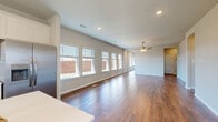 Located in the Evergreen community of Saginaw, TX, this two-story home offers four bedrooms and four full bathrooms across a well-designed layout. The main floor commands the majority of the living space, featuring an open-concept living area bathed in natural light from a row of large windows. Rich wood-look tile flooring runs throughout the main level, complemented by neutral gray walls, recessed lighting, and a ceiling fan that adds comfort to the airy living room. An elegant arched passageway connects the living spaces seamlessly. The kitchen is outfitted with crisp white shaker-style cabinetry extending to the ceiling, white quartz countertops, a subway tile backsplash, and stainless steel appliances including a gas range, over-the-range microwave, and refrigerator. A dedicated laundry room houses a full-size washer and dryer. The upper floor hosts the remaining bedrooms, each carpeted and fitted with closets featuring built-in shelving and hanging rods. Bathrooms are finished with marble-look tile flooring, dual-sink white vanities with quartz countertops, and tiled walk-in showers. Each bedroom includes its own dedicated closet. The property also features a generously sized, fully fenced backyard, offering ample outdoor space.