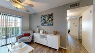 This single-floor, 2-bedroom, 1-bathroom residence offers a thoughtfully arranged layout that maximizes every square foot of its compact footprint. Wood-look flooring flows consistently throughout the unit, lending a cohesive and contemporary feel to each room.

The living room serves as the heart of the home, featuring a ceiling fan, large sliding glass doors with vertical blinds that invite natural light and offer outdoor views of surrounding greenery. The space transitions into a combined dining area, which conveniently shares its wall with an in-unit laundry nook housing a full-size washer and dryer set with built-in shelving above — a practical and desirable feature.

The galley-style kitchen is efficiently designed with ample cabinetry, light marble-patterned countertops, a double-basin sink, and black appliances including a refrigerator and electric range, all complemented by a window for natural light.

Both bedrooms are comfortable and bright, each equipped with ceiling fans. The primary bedroom offers a closet, while the shared bathroom features a wide vanity with generous cabinetry, a large mirror, and warm overhead lighting. A closet adjacent to the bathroom provides additional storage. The hallway connects all rooms in a straightforward and functional layout.