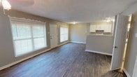 Located at 2468 Laughlin Dr in Dallas, TX, this two-story home offers a functional and comfortable layout spread across two levels. The main floor welcomes you with a bright, open living area featuring durable wood-look flooring, neutral gray walls, and a textured ceiling. Large windows along the front of the living room allow ample natural light to fill the space, creating an inviting atmosphere. A peninsula counter seamlessly connects the living area to the kitchen, which is designed in a galley style with white cabinetry, granite-look countertops, a mosaic tile backsplash, and white appliances including a range and refrigerator. The lower level also includes a spacious secondary living or flex area with wood-look flooring and staircase access to the upper floor. The upper level features carpeted bedrooms with ceiling fans, neutral-toned walls, and windows that bring in natural light. The bathroom is well-appointed with wood-look flooring, a tiled tub-and-shower surround featuring a decorative mosaic accent border, and brushed nickel fixtures. Additional bathrooms include clean white finishes with brushed nickel hardware. Overall, the home presents a clean, move-in-ready aesthetic with consistent neutral tones throughout.