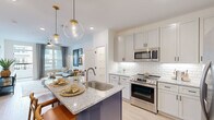 Located at 445 51st St in Wilmington, NC, this thoughtfully designed one-bedroom, one-bathroom residence offers a cohesive open-concept layout that maximizes both function and style. Light hardwood flooring flows throughout the main living areas, anchoring a bright and airy atmosphere enhanced by recessed lighting and large windows.

The kitchen is a standout feature, showcasing white shaker cabinetry with matte black hardware, a classic subway tile backsplash, granite countertops, and a full suite of stainless steel appliances. A navy-accented island with a undermount sink and globe pendant lighting above serves as the centerpiece, seamlessly connecting to the living and dining area.

The living room offers a relaxed, coastal-inspired ambiance with wall sconces, a ceiling fan, and access to a private balcony through a glass-panel door, bringing in ample natural light and outdoor views.

The bedroom is a serene retreat, comfortably proportioned with a large window, ceiling fan, and plush carpeting. The bathroom continues the refined aesthetic with granite countertops, gray cabinetry, matte black fixtures, and clean white tile work. A dedicated closet and in-unit laundry add practical convenience to this well-rounded Wilmington residence.