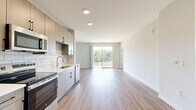 Located at 2200 Cascade Pointe Blvd in Charlotte, NC, this well-appointed one-bedroom, one-bathroom residence offers a thoughtfully designed single-floor layout with modern finishes throughout. Light-toned luxury vinyl plank flooring flows seamlessly across the entire unit, creating a cohesive and contemporary aesthetic.

The open-concept kitchen and living area serves as the heart of the home. The kitchen is outfitted with stainless steel appliances — including a range, microwave, refrigerator, and dishwasher — complemented by light wood-grain cabinetry with matte black hardware, white quartz countertops, and a striking marble-style subway tile backsplash. The living area extends naturally from the kitchen and opens to a private balcony through a sliding glass door, allowing for generous natural light and outdoor views.

The spacious primary bedroom features a ceiling fan, a large window with natural light, and direct access to the bathroom. The bathroom is finished with a wood-grain vanity, white quartz countertop, and a glass-enclosed walk-in shower adorned with white subway tile.

A dedicated laundry room houses a stacked washer and dryer unit, adding everyday convenience. The overall ambiance of the space is clean, bright, and modern, ideal for comfortable urban living in Charlotte.