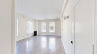Located at 840 S Serrano Ave in the Koreatown neighborhood of Los Angeles, Unit 300 is a thoughtfully laid-out single-floor residence featuring a living room, dining room, kitchen, bathroom, hallway, and four closets. The living and dining areas are bathed in natural light through multiple large windows dressed with vertical blinds, and polished concrete floors reflect the brightness throughout, creating an airy, open atmosphere. A classic cast-iron radiator adds a charming vintage touch to the living space. The galley-style kitchen is well-appointed with white cabinetry, a warm golden tile backsplash, tile countertops, a gas range, and a full-size refrigerator, with track lighting overhead. The bathroom is a standout feature, showcasing bold deep-navy subway tile wainscoting surrounding a soaking tub, paired with marble-look tile flooring and a bright window that fills the room with natural light. Generous storage is provided through four closets, including a dedicated dressing area with built-in cabinetry, a vanity with a mirror, and a wardrobe closet. The unit's neutral palette and consistent concrete flooring tie the spaces together cohesively throughout.