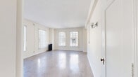 Located at 840 S Serrano Ave in the Koreatown neighborhood of Los Angeles, Unit 300 is a thoughtfully laid-out single-floor residence featuring a living room, dining room, kitchen, bathroom, hallway, and four closets. The living and dining areas are bathed in natural light through multiple large windows dressed with vertical blinds, and polished concrete floors reflect the brightness throughout, creating an airy, open atmosphere. A classic cast-iron radiator adds a charming vintage touch to the living space. The galley-style kitchen is well-appointed with white cabinetry, a warm golden tile backsplash, tile countertops, a gas range, and a full-size refrigerator, with track lighting overhead. The bathroom is a standout feature, showcasing bold deep-navy subway tile wainscoting surrounding a soaking tub, paired with marble-look tile flooring and a bright window that fills the room with natural light. Generous storage is provided through four closets, including a dedicated dressing area with built-in cabinetry, a vanity with a mirror, and a wardrobe closet. The unit's neutral palette and consistent concrete flooring tie the spaces together cohesively throughout.