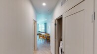 This thoughtfully designed single-floor residence offers a clean, contemporary aesthetic throughout. The entry hallway provides convenient access to all areas of the home, with in-unit laundry tucked neatly behind a door for easy access.

The open-plan kitchen is a standout feature, outfitted with two-tone cabinetry — warm wood lower cabinets paired with crisp white upper cabinets — complemented by white quartz countertops and stainless steel appliances including a range, microwave, refrigerator, and dishwasher. Large windows and a sliding glass door flood the kitchen with natural light while offering views of the outdoor patio and surrounding greenery.

The living area is bright and welcoming, with oversized windows and a sliding glass door that open to a private patio overlooking a landscaped courtyard, seamlessly blending indoor and outdoor living. Light wood-style flooring flows throughout the space, enhancing the airy feel.

The two bedrooms are comfortably sized, each with windows that invite natural light. The two bathrooms are finished with a neutral palette, featuring modern white vanities with under-mount sinks, large mirrors, and hexagonal tile flooring. One bathroom includes a walk-in shower with glass doors, while the other offers a shower-tub combination.