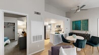 This thoughtfully designed 2-bedroom residence spans a single floor and offers a comfortable, functional layout with modern finishes throughout. The open-concept living area features vaulted ceilings that lend a sense of spaciousness, light wood flooring, and generous natural light from large windows fitted with blinds. A ceiling fan adds to the airy feel of the space.

The kitchen is outfitted with crisp white cabinetry, stainless steel appliances including a refrigerator, range, microwave, and dishwasher, as well as light countertops and a peninsula with seating that flows naturally into the dining area. A second kitchen space offers additional utility and flexibility. Conveniently located in-unit laundry with a top-loading washer is tucked neatly adjacent to the kitchen area.

The primary bedroom is a well-proportioned retreat with plush carpeting, a large window for natural light, and access to a closet. The second bedroom is similarly appointed, featuring carpet flooring, bright windows, and a warm, comfortable ambiance. Both rooms offer a quiet, restful atmosphere. The neutral gray and white color palette used throughout the residence creates a cohesive, modern aesthetic that feels both clean and inviting.