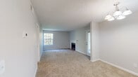 This single-floor residence offers a thoughtfully arranged layout with well-defined living spaces throughout. The living room serves as a central gathering area, highlighted by a classic fireplace with a white mantel, neutral-toned carpet flooring, and a textured ceiling. Natural light filters in through multiple windows, while a door provides direct access to an outdoor area. A chandelier adds a touch of warmth to the adjoining dining area, which connects seamlessly to the kitchen.

The kitchen is well-appointed with rich, dark wood cabinetry, light-toned countertops, and wood-look flooring. Black appliances — including a refrigerator, electric range with overhead ventilation, and dishwasher — complement the cabinetry. A double-basin stainless steel sink sits beneath a window, and an open wall shelf offers additional utility space.

The bedrooms are carpeted and filled with natural light from large windows, providing a comfortable and quiet retreat. Louvered closet doors add a classic detail to the bedroom spaces. The bathroom features a vanity with dark wood cabinetry and light countertops, a wide mirror, and a separate water closet with a full tub and shower combination. Throughout the home, textured ceilings, crisp white trim, and a consistent neutral color palette create a cohesive and clean aesthetic.